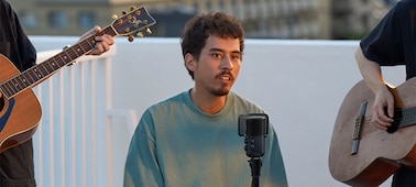 Imagen de uso de un hombre cantando con el micrófono en un soporte con un guitarrista a cada lado de él