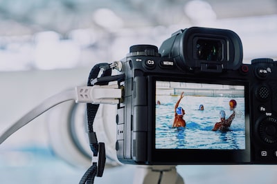 Imagen de uso de la cámara montada en un tripié y conectada a un cable LAN que hace capturas a un partido de waterpolo con una imagen en vivo que se muestra en el monitor LCD