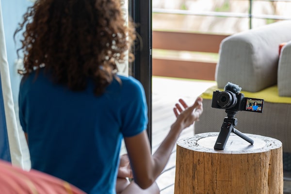 Imagen de una modelo filmándose con una cámara en un minitripié sobre una mesa y una pantalla de ángulo variable extendida para verse.