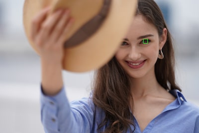 Imagen de una modelo sosteniendo un sombrero que tapa parte de su cara, con un marco de AF superpuesto en un ojo