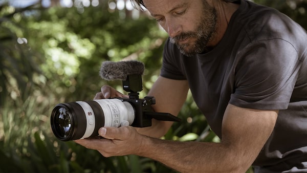 Foto de un hombre grabando un video de forma manual con un lente teleobjetivo