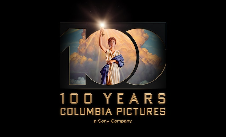 Imagen del n.º 100 con una persona sosteniendo una linterna contra un fondo de nubes y la leyenda “100 años de Columbia Pictures” debajo