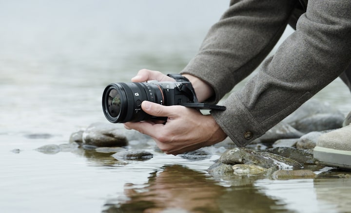 Imagen que muestra a un usuario con la α7CII con el G Lens FE 24-50 mm F2.8 cerca de un río. El usuario está capturando imágenes desde abajo